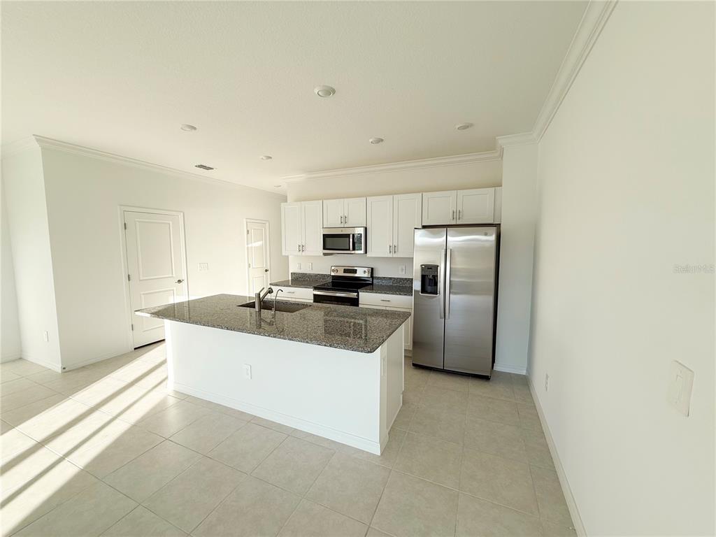 A kitchen with white cabinets, granite countertops, a center island, and stainless steel appliances — 9001 GALLANTREE PLACE, LAND O LAKES, FL