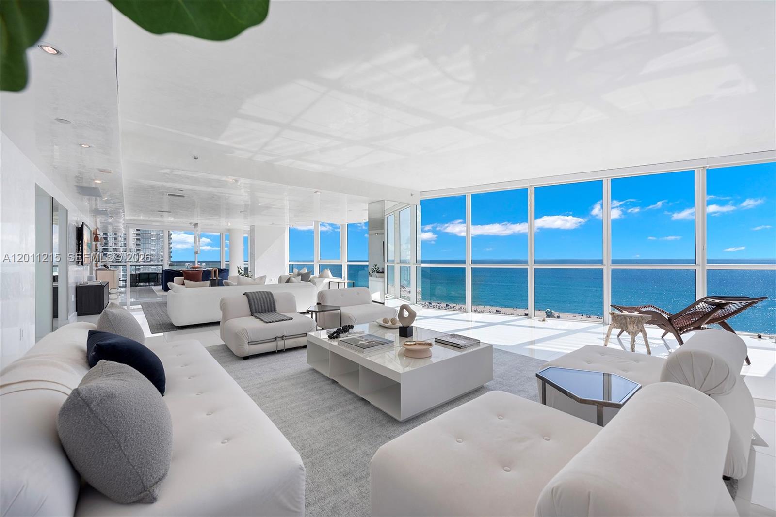 A bright, modern living room features white furniture, a large coffee table, and floor-to-ceiling windows — 101 20th St # 1707, Miami Beach FL 33139, MIAMI BEACH, FL