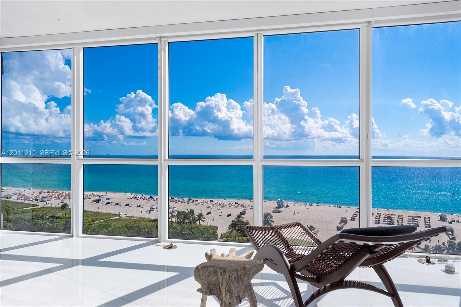 A room with white tile floors and a lounge chair overlooks a beach and ocean — 101 20th St # 1707, Miami Beach FL 33139, MIAMI BEACH, FL