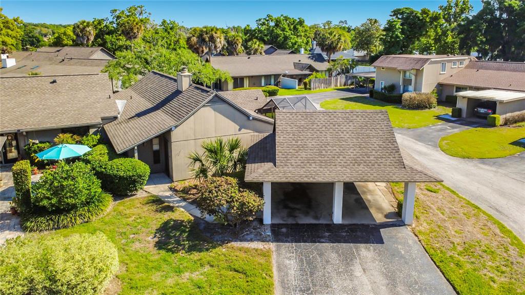 An aerial view of a single-story house with a detached carport and a paved driveway — 1921 ABBINGTON STREET UNIT 23C, APOPKA, FL