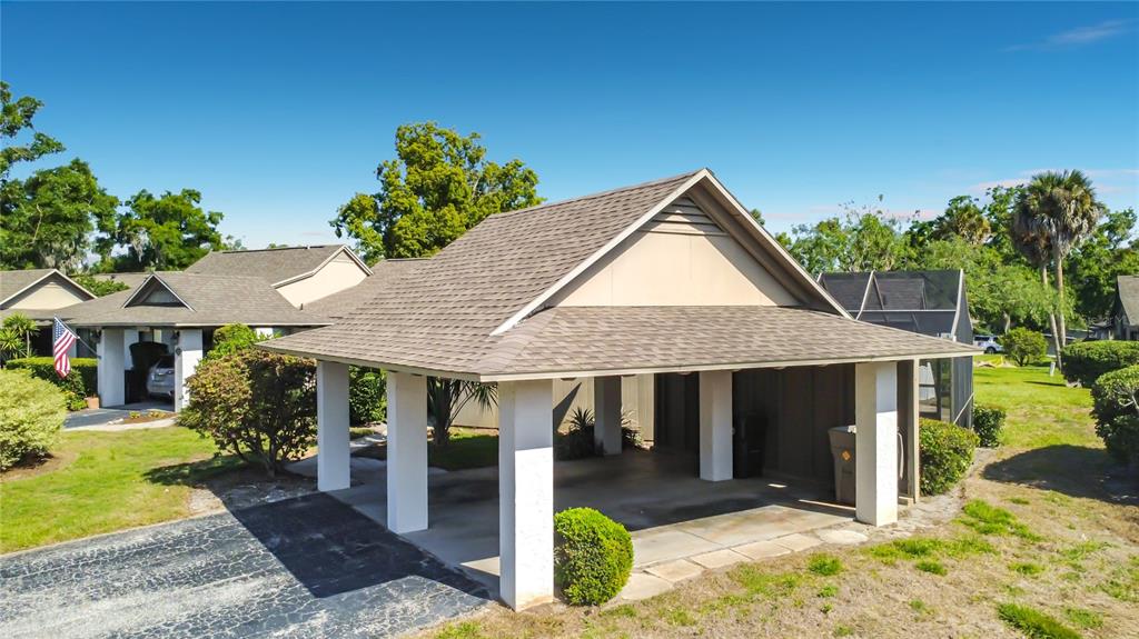 A detached carport with a shingled roof stands in front of a residential home — 1921 ABBINGTON STREET UNIT 23C, APOPKA, FL