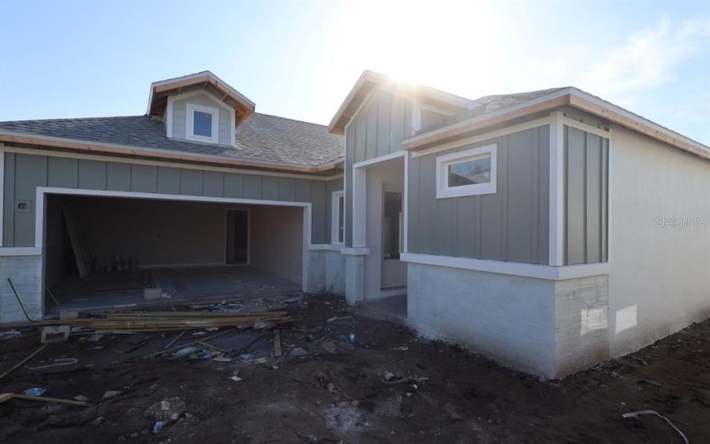 A partially constructed house with green board-and-batten siding, a garage, and a front entryway — 5261 COLONY VISTA DRIVE, APOLLO BEACH, FL