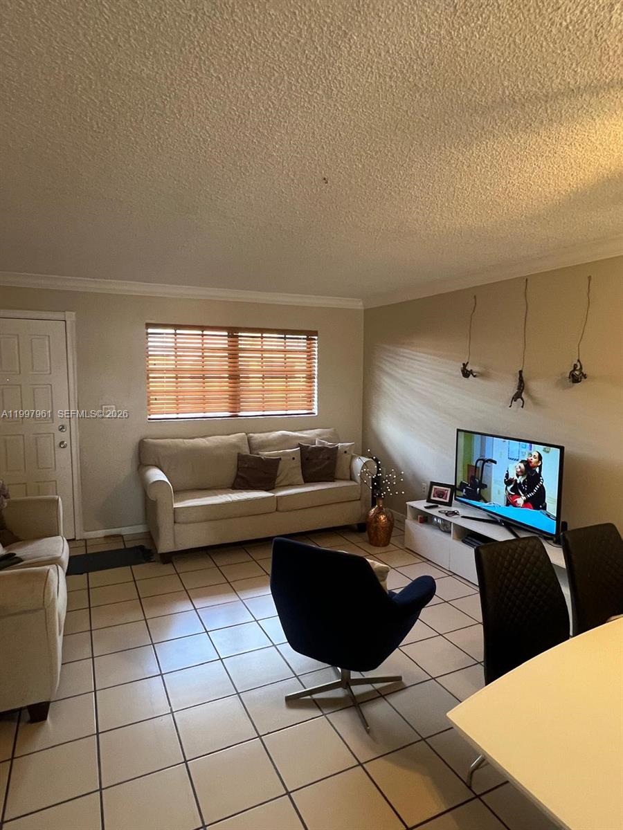 A living room features a beige sofa, a television on a stand, and tiled flooring — 1298 W 51st Pl # 29, Hialeah FL 33012, HIALEAH, FL