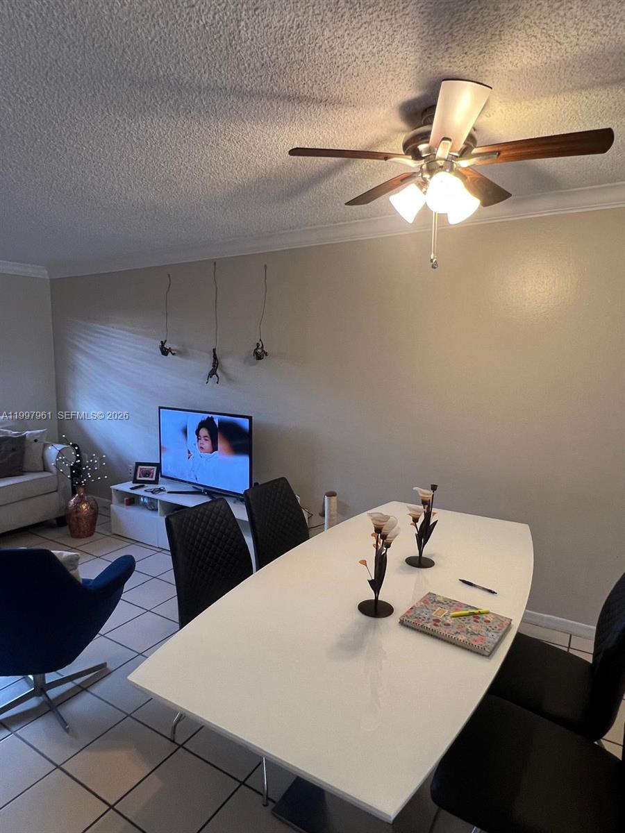 A dining area with a white table and black chairs sits before a living room — 1298 W 51st Pl # 29, Hialeah FL 33012, HIALEAH, FL