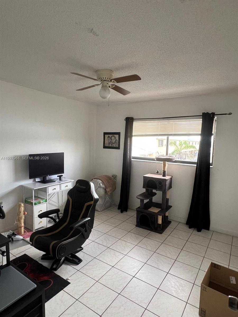 A room with white walls, tiled flooring, a ceiling fan, a desk, and a cat tree — 1298 W 51st Pl # 29, Hialeah FL 33012, HIALEAH, FL