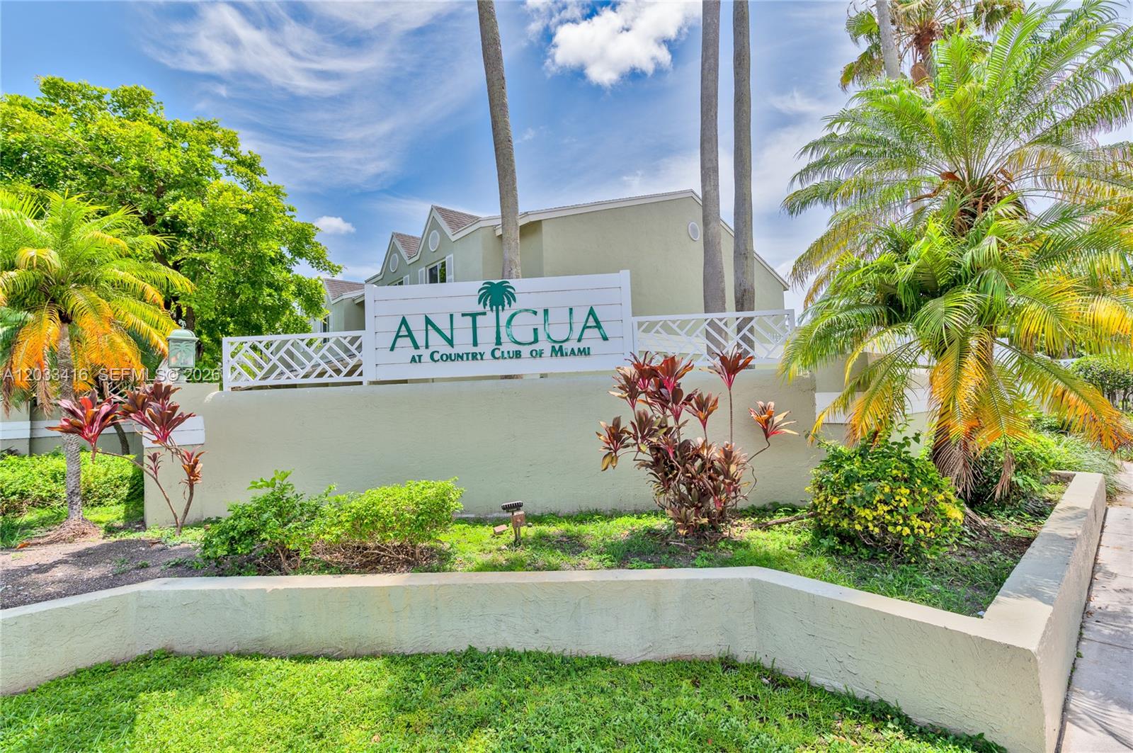 A sign for Antigua at Country Club of Miami stands before a building and palm trees — 17485 NW 67th Ct # 21, Hialeah FL 33015, HIALEAH, FL