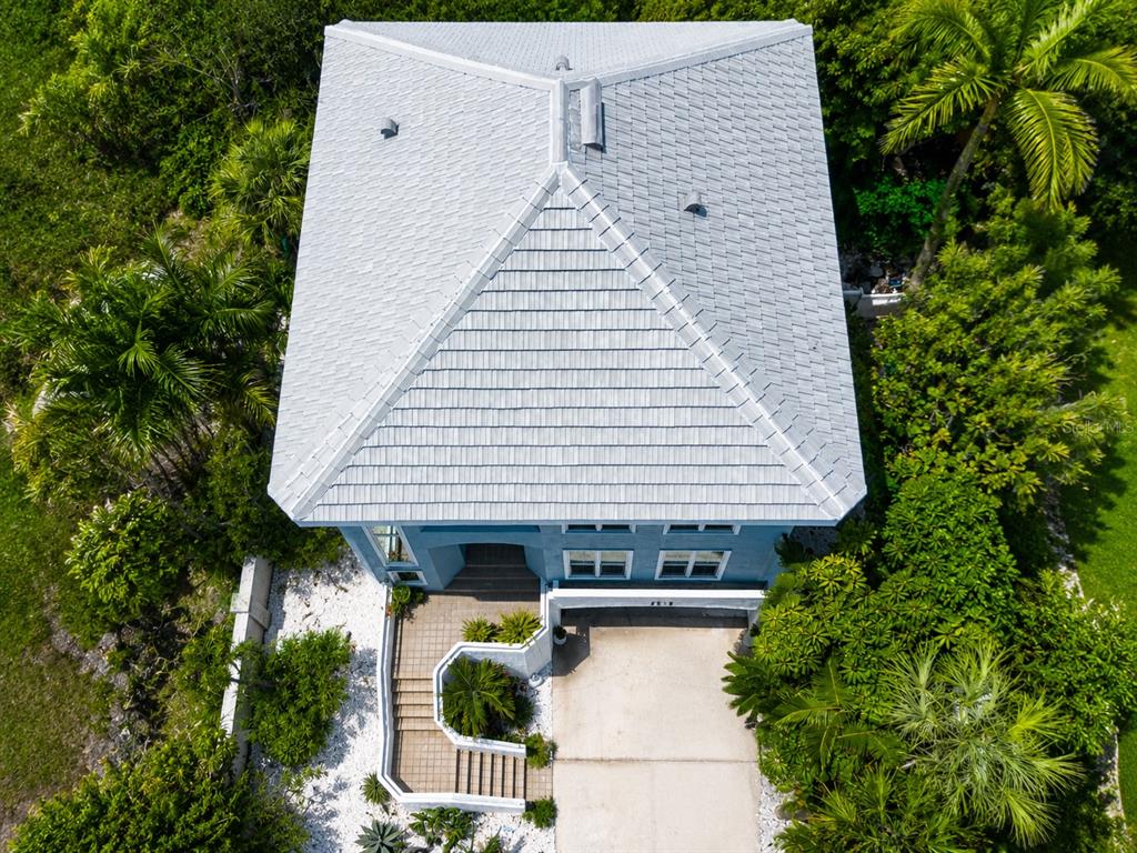 An aerial view shows a blue house with a light-colored roof, driveway, and surrounding landscaping — 3915 SOMERSET DRIVE UNIT 9, SARASOTA, FL