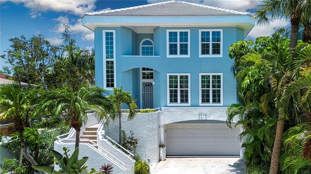 A light blue two-story house features a white base, a garage, and an exterior staircase — 3915 SOMERSET DRIVE UNIT 9, SARASOTA, FL