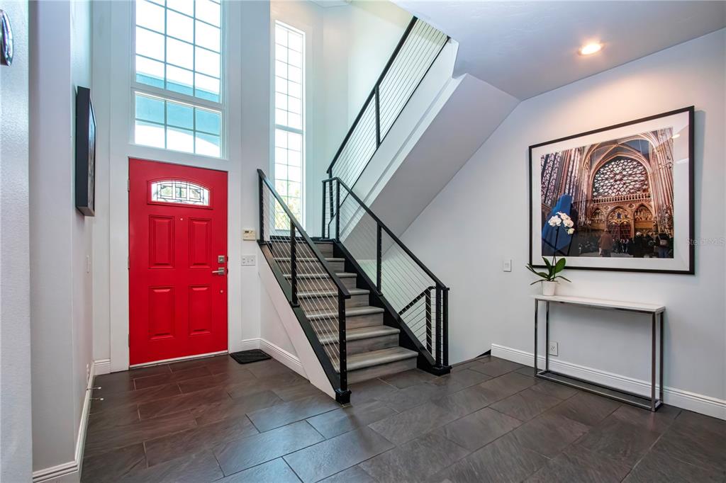 An entryway features a red front door, a staircase with cable railings, and tiled floors — 3915 SOMERSET DRIVE UNIT 9, SARASOTA, FL