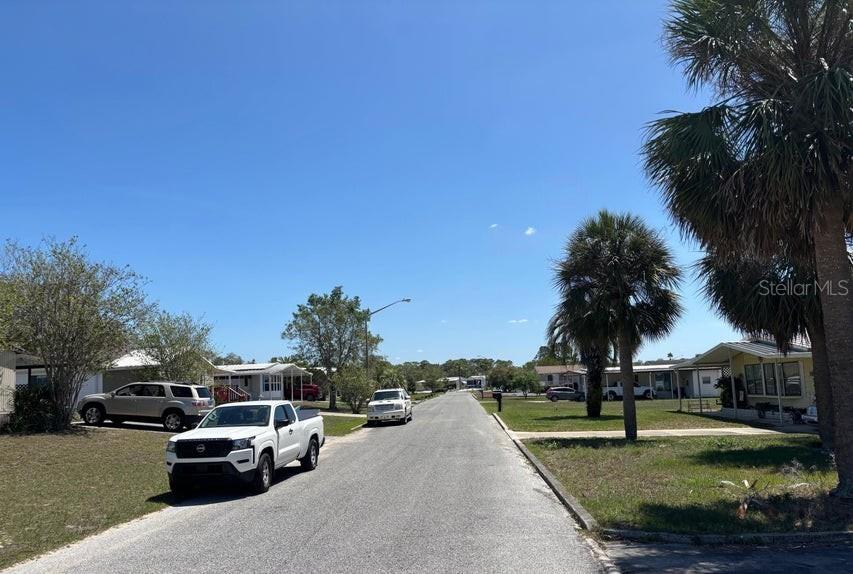 A paved street runs through a residential area with parked vehicles and palm trees — 14405 DIABLO DRIVE, BROOKSVILLE, FL