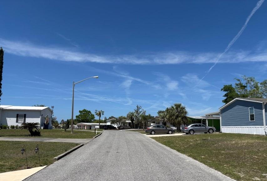 A paved street runs between residential homes under a clear blue sky — 14405 DIABLO DRIVE, BROOKSVILLE, FL