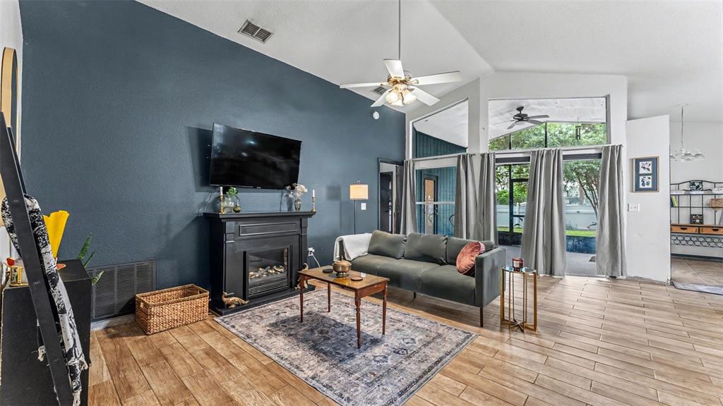 A living room features a dark blue accent wall, fireplace, gray sofa, and tile flooring — 2723 SUNDANCE CIRCLE, MULBERRY, FL