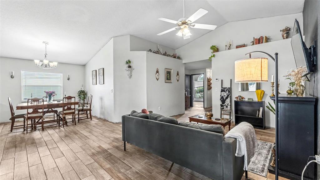 A living room and dining area feature vaulted ceilings, wood-look tile flooring, and neutral walls — 2723 SUNDANCE CIRCLE, MULBERRY, FL