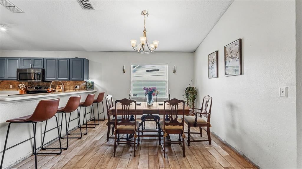 A dining area with a wooden table, chairs, and a breakfast bar with stools — 2723 SUNDANCE CIRCLE, MULBERRY, FL