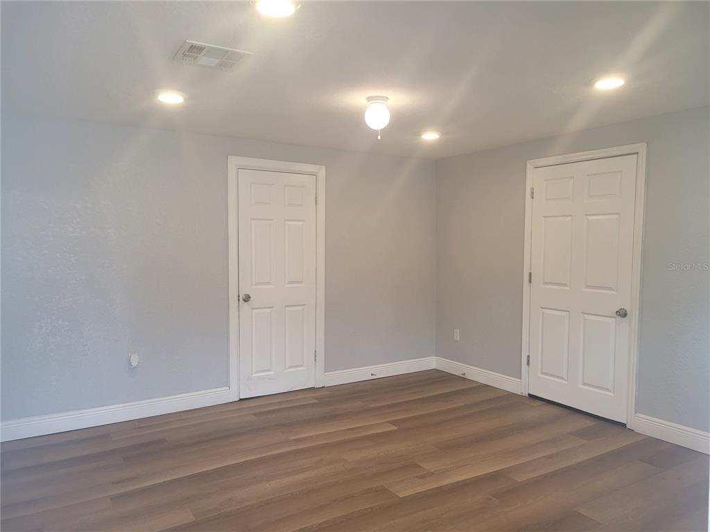 An empty room with light gray walls, wood-look flooring, and two white interior doors — 1320 S OLEANDER AVENUE, SANFORD, FL