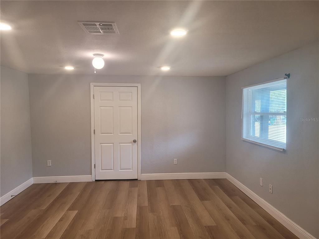 A room with light gray walls, wood-look flooring, a white door, and a window — 1320 S OLEANDER AVENUE, SANFORD, FL