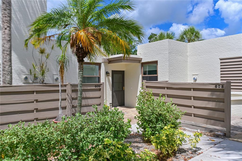 The exterior of a residential building features a front entrance with a palm tree and fencing — 609 WOODLAWN DRIVE, BRADENTON, FL