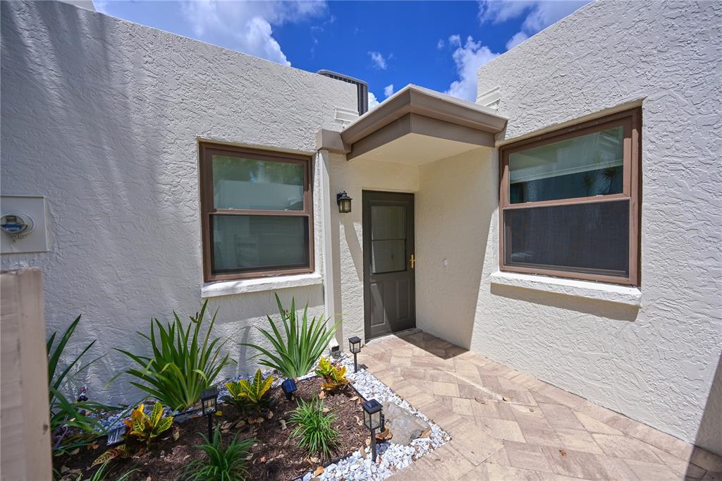 A paved walkway leads to a front door flanked by two windows and landscaping — 609 WOODLAWN DRIVE, BRADENTON, FL