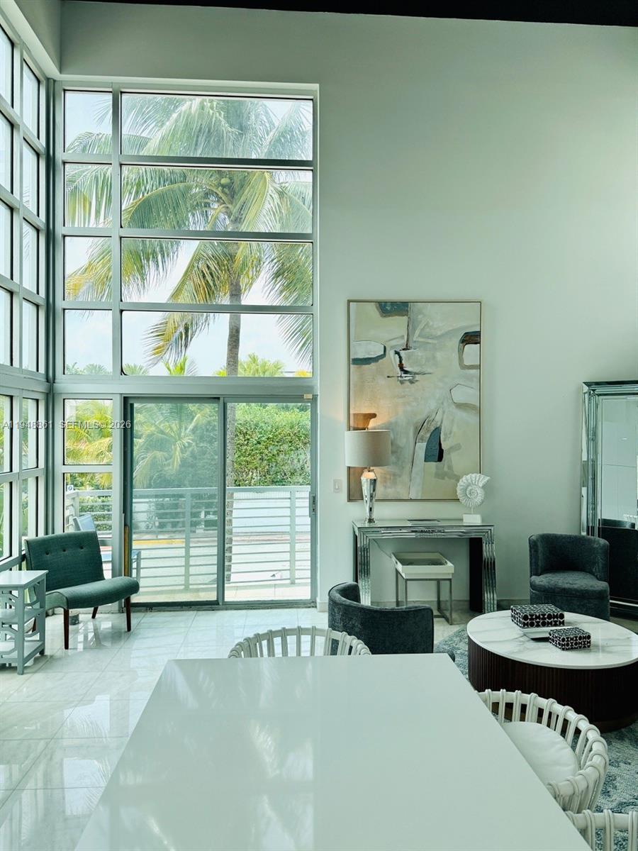 A bright living area features floor-to-ceiling windows, white tile floors, and modern furniture — 7700 Collins Ave # 5, Miami Beach FL 33141, MIAMI BEACH, FL