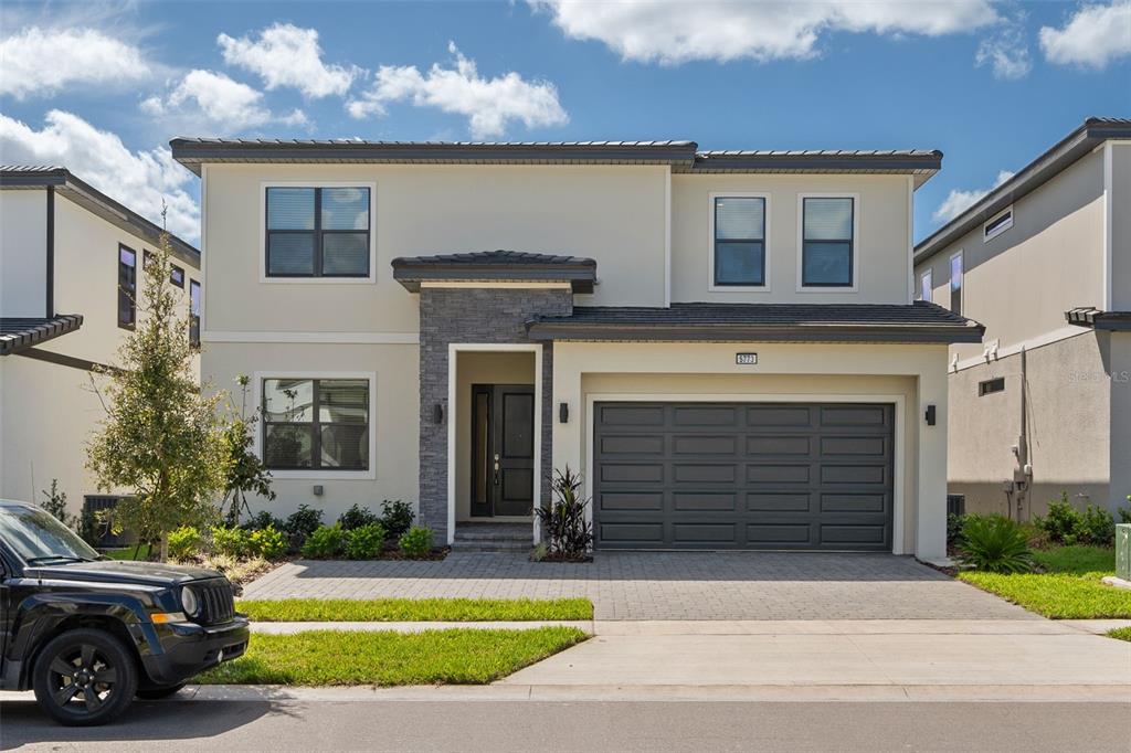 A two-story house with a stone-accented entryway, a two-car garage, and a paved driveway — 5773 HIGH SEAS DRIVE, ORLANDO, FL