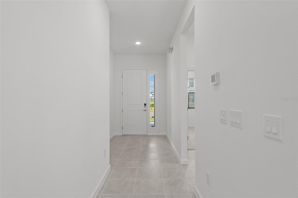 A bright entryway features white walls, tile flooring, and a front door with a sidelight — 5773 HIGH SEAS DRIVE, ORLANDO, FL