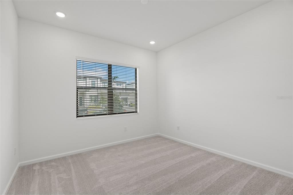 An empty bedroom features white walls, gray carpet, recessed lighting, and a window with blinds — 5773 HIGH SEAS DRIVE, ORLANDO, FL