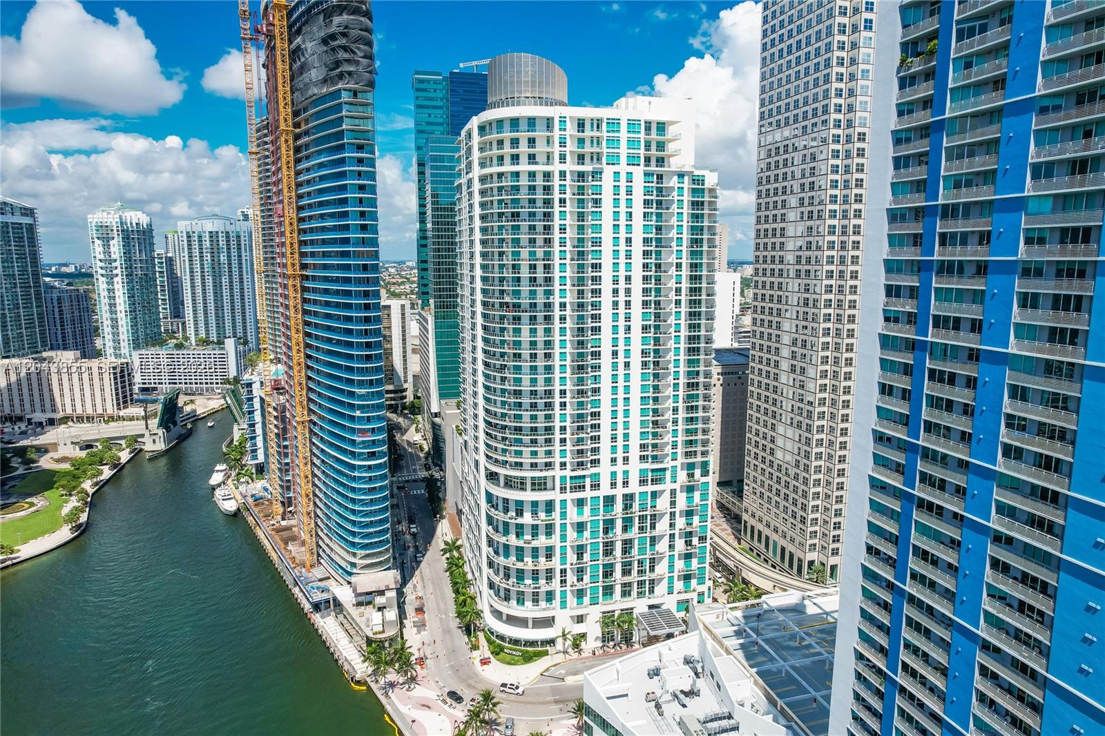 A modern living room features a spiral staircase, floor-to-ceiling windows, and a gray sectional sofa — 300 S Biscayne Blvd # 612, Miami FL 33131, MIAMI, FL
