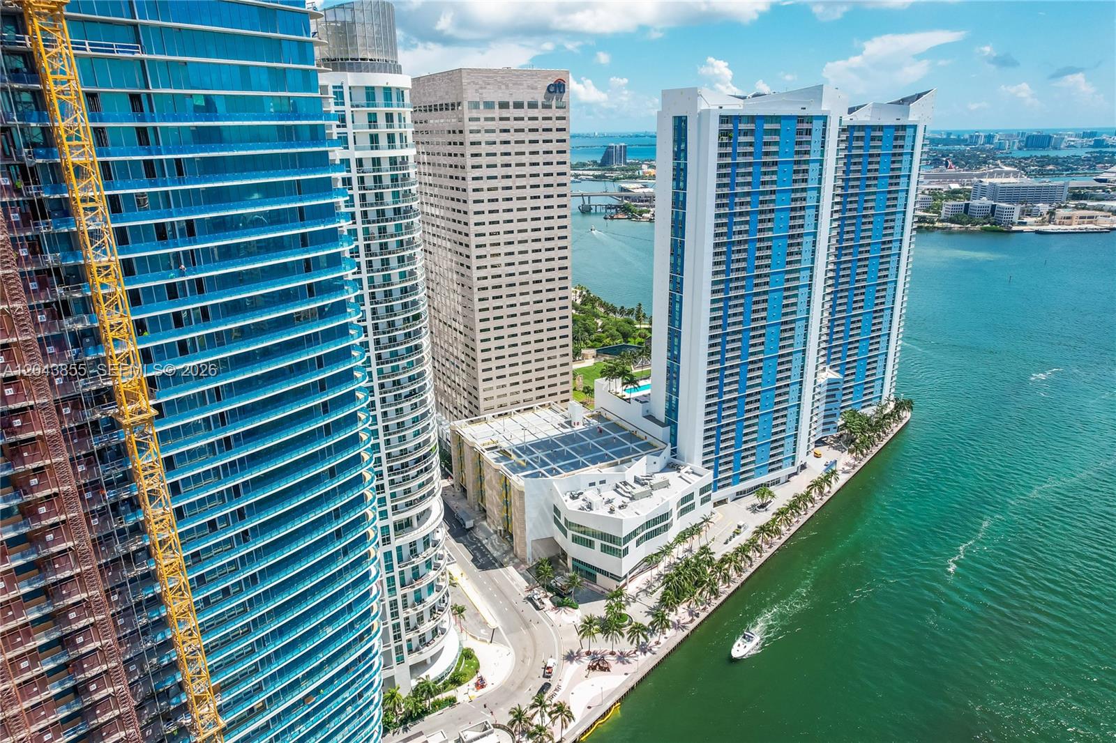 A balcony view overlooking a turquoise waterway, modern high-rise buildings, and a clear blue sky — 300 S Biscayne Blvd # 612, Miami FL 33131, MIAMI, FL