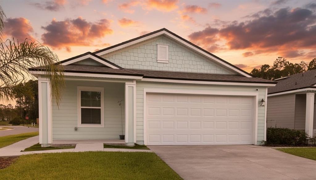 A light green single-story house with a two-car garage and a covered front porch — 1 CADDY COURT, BUNNELL, FL