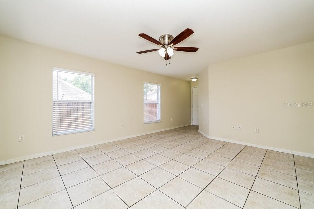 An empty room features beige walls, light-colored tile flooring, two windows, and a ceiling fan — 11805 PRICKLY PEAR WAY, SEFFNER, FL
