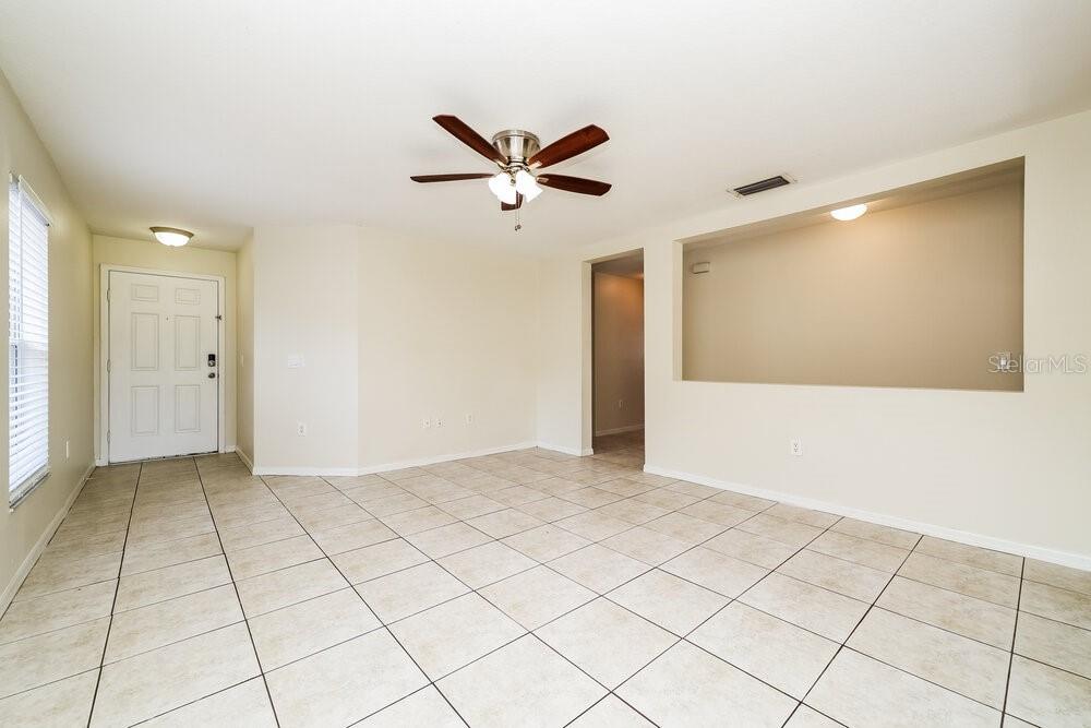 An empty room features light-colored tile flooring, a ceiling fan, and a large wall cutout — 11805 PRICKLY PEAR WAY, SEFFNER, FL