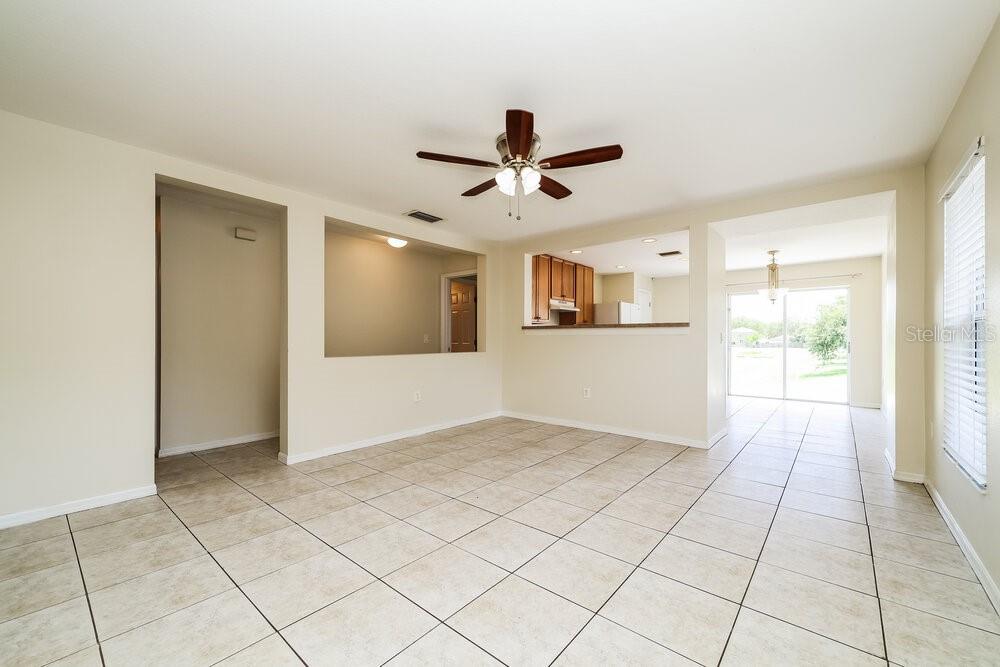 An open-concept living area features light-colored tile flooring, a ceiling fan, and a pass-through window — 11805 PRICKLY PEAR WAY, SEFFNER, FL