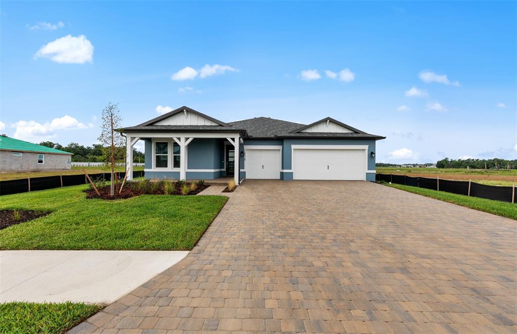 A blue single-story house with a paved driveway and a two-car garage — 16518 ENNIS PLACE, BRADENTON, FL