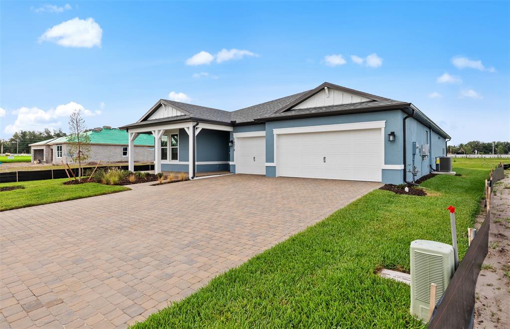 A blue single-story house with a paver driveway and a three-car garage — 16518 ENNIS PLACE, BRADENTON, FL