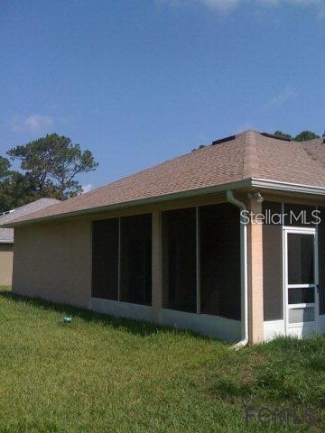 The exterior of a house features a screened-in porch and a tan stucco wall — 60 PERTHSHIRE LANE, PALM COAST, FL