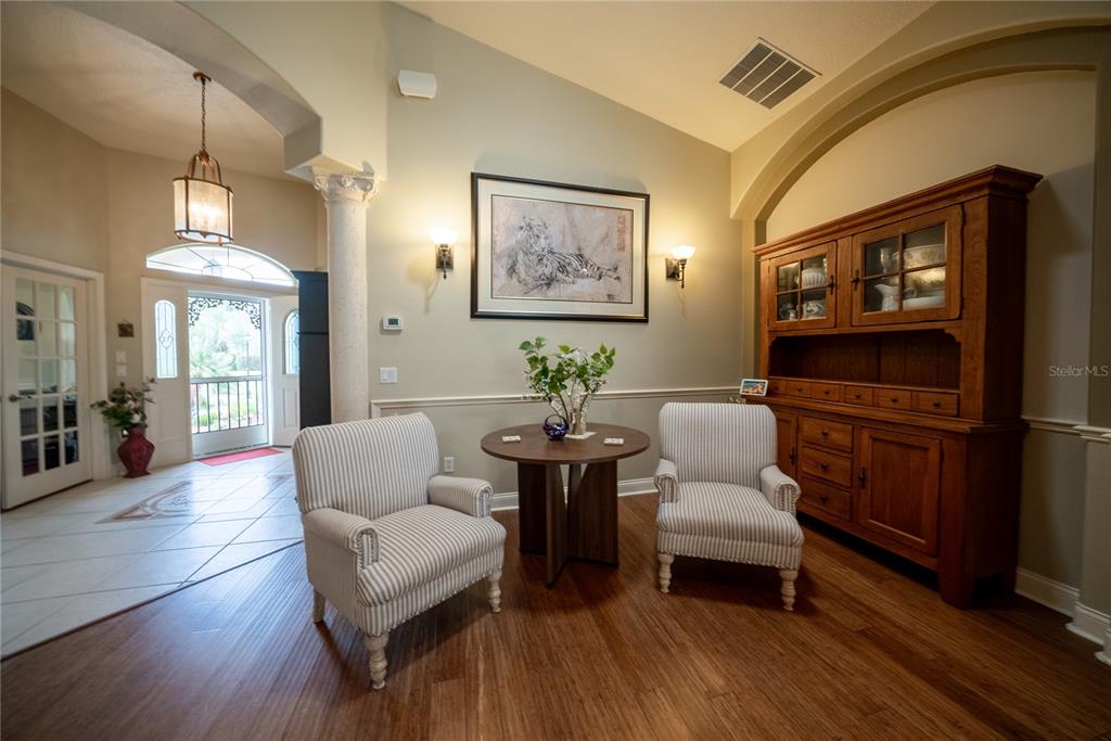 A foyer features a wood floor, two striped armchairs, a small table, and a wooden hutch — 710 LAKE DIAMOND AVENUE, OCALA, FL