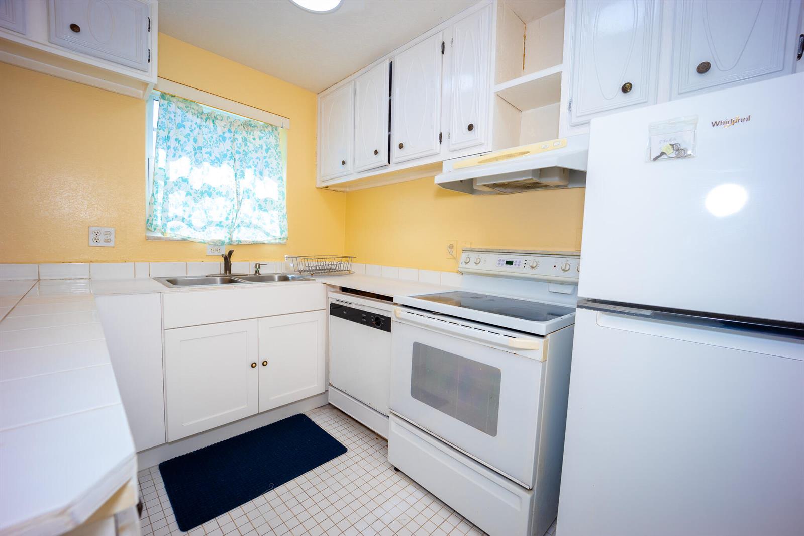 A kitchen with yellow walls, white cabinets, white appliances, and a tiled floor — 3240 Ridge Hill Road # C, Boynton Beach FL 33435, BOYNTON BEACH, FL