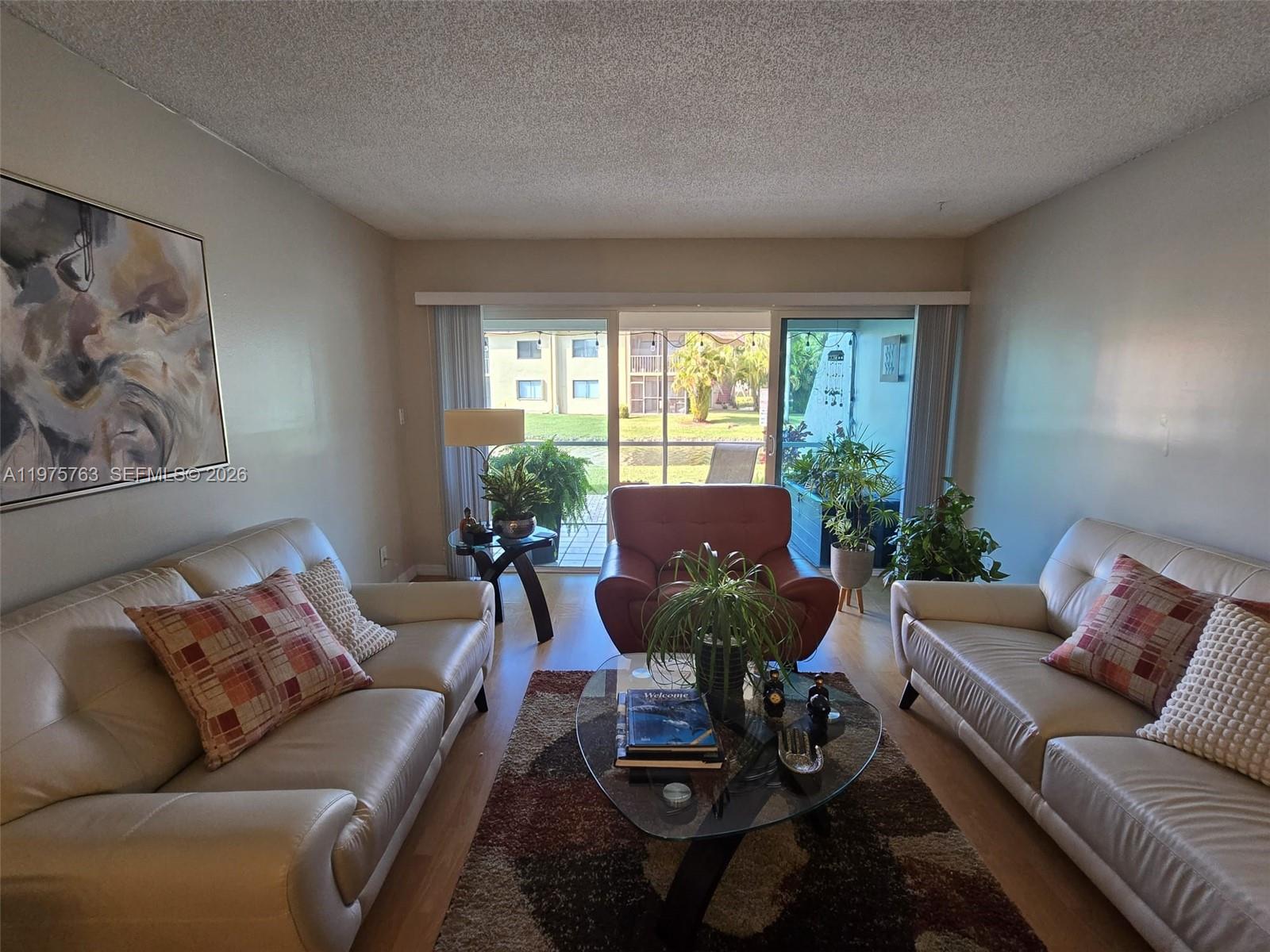 A living room features two leather sofas, a glass coffee table, and sliding glass doors — 140 Lakeview Dr # 111, Weston FL 33326, WESTON, FL