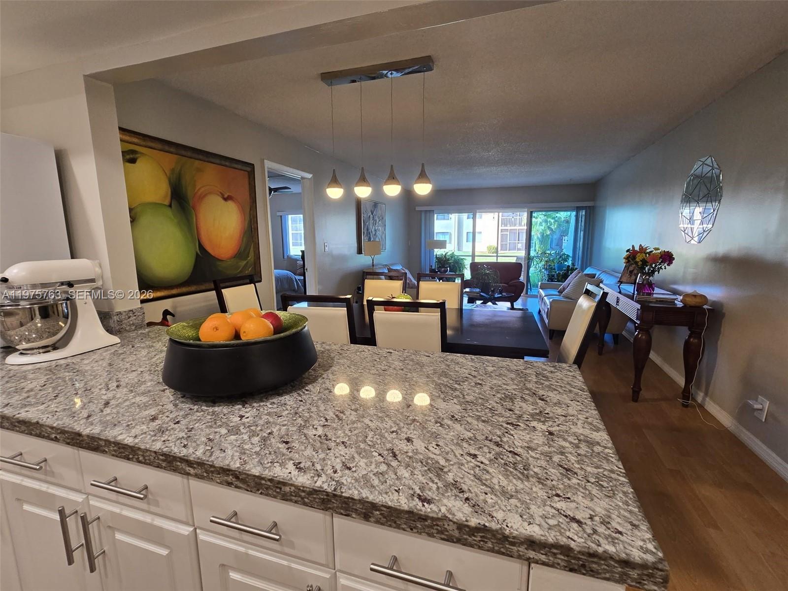 A kitchen island with granite countertops overlooks a dining area and living room — 140 Lakeview Dr # 111, Weston FL 33326, WESTON, FL