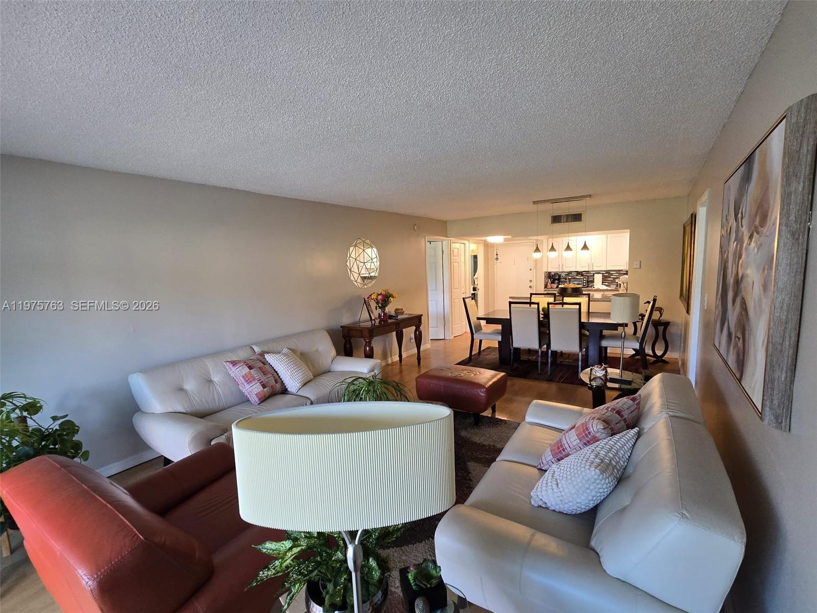 A living room and dining area feature white leather sofas, a dining table, and artwork — 140 Lakeview Dr # 111, Weston FL 33326, WESTON, FL