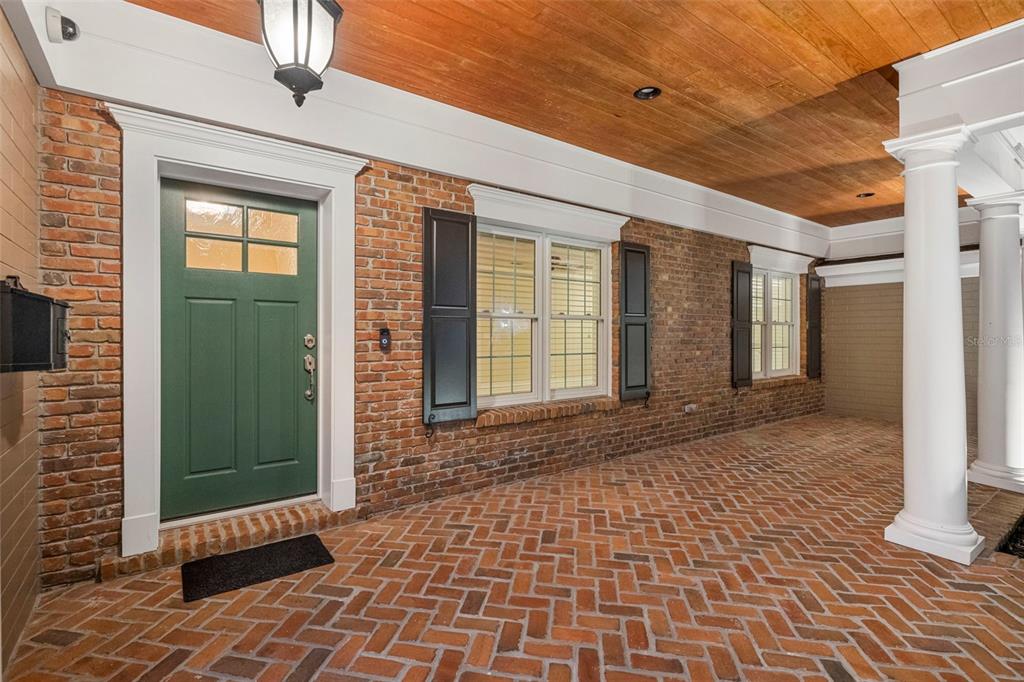 A brick porch features a green front door, white columns, and a wood-paneled ceiling — 2410 LAKE SHORE DRIVE, ORLANDO, FL