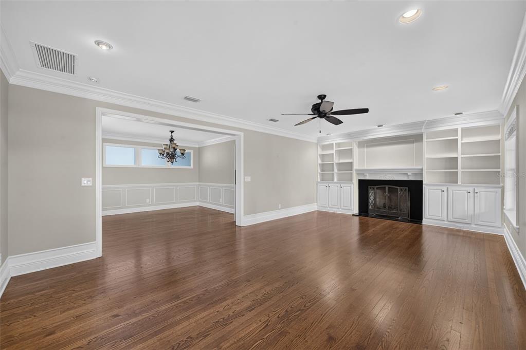 A living room with hardwood floors, a fireplace, built-in shelving, and an adjacent dining area — 2410 LAKE SHORE DRIVE, ORLANDO, FL