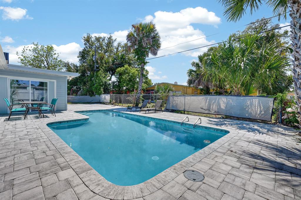 A backyard features a rectangular swimming pool surrounded by a paved patio and palm trees — 1030 ALICE DRIVE, DAYTONA BEACH, FL