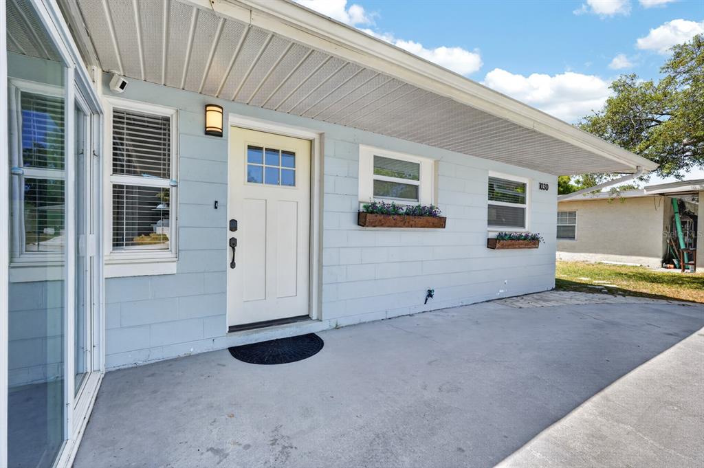 A light blue exterior wall features a white front door, two windows, and flower boxes — 1030 ALICE DRIVE, DAYTONA BEACH, FL