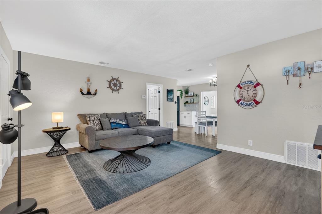 A living room features a gray sectional sofa, a round coffee table, and nautical wall decor — 1030 ALICE DRIVE, DAYTONA BEACH, FL