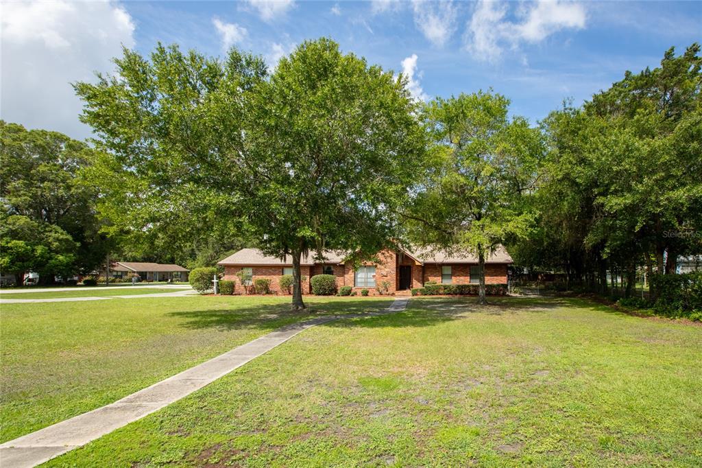 A single-story brick house with a front walkway sits on a large, grassy lot — 1619 RAIFORD ROAD, STARKE, FL