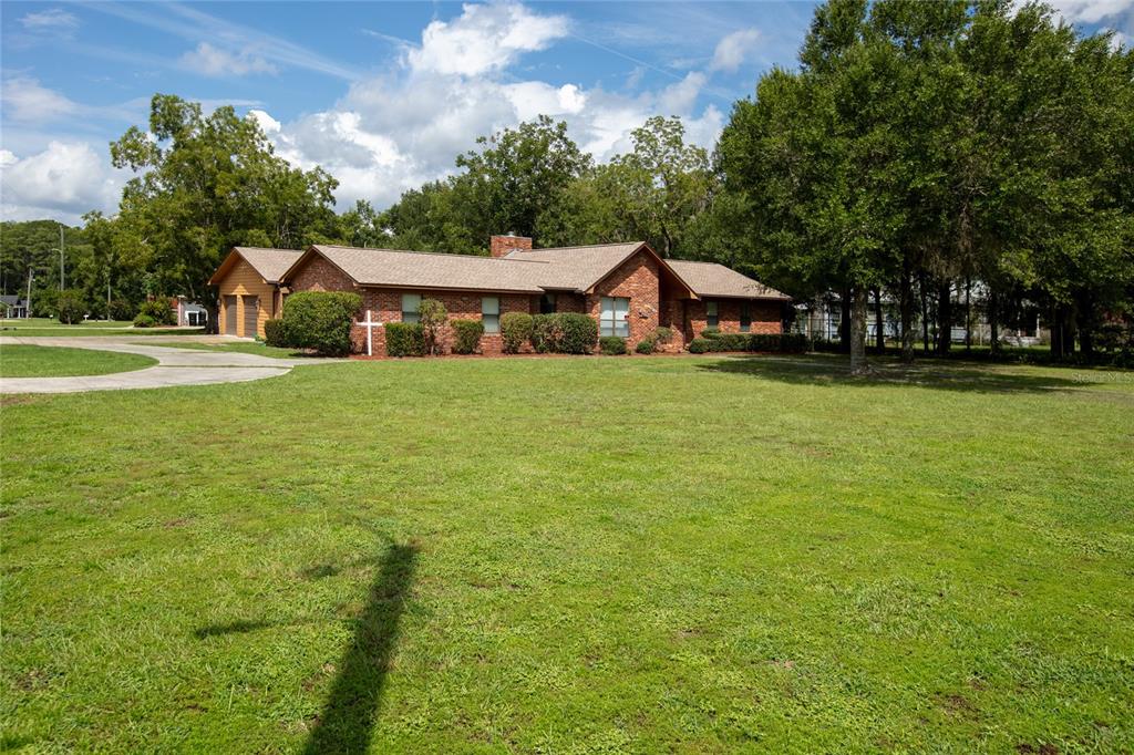 A single-story brick house with a shingled roof sits on a large, grassy lawn — 1619 RAIFORD ROAD, STARKE, FL