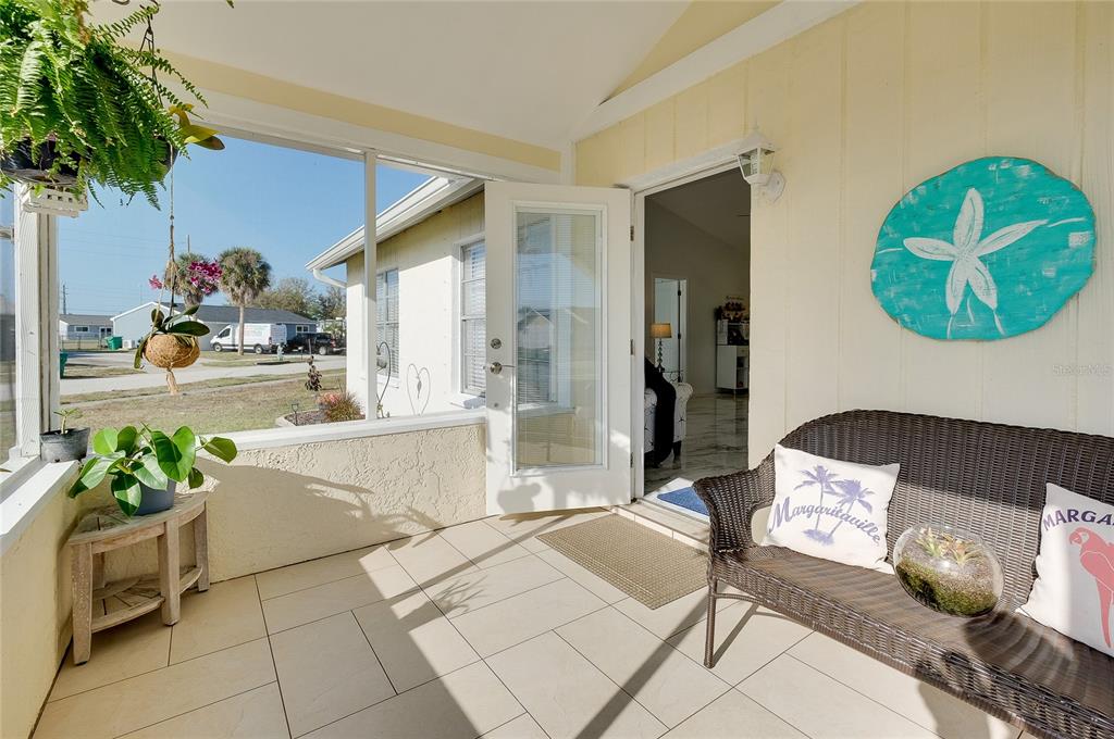 A screened-in porch with tile flooring, wicker furniture, and a view of the street — 6433 GRANGER ROAD, PORT CHARLOTTE, FL