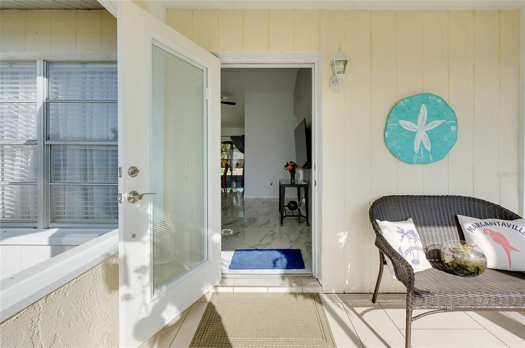 An open front door reveals a tiled interior entryway from a covered porch with seating — 6433 GRANGER ROAD, PORT CHARLOTTE, FL