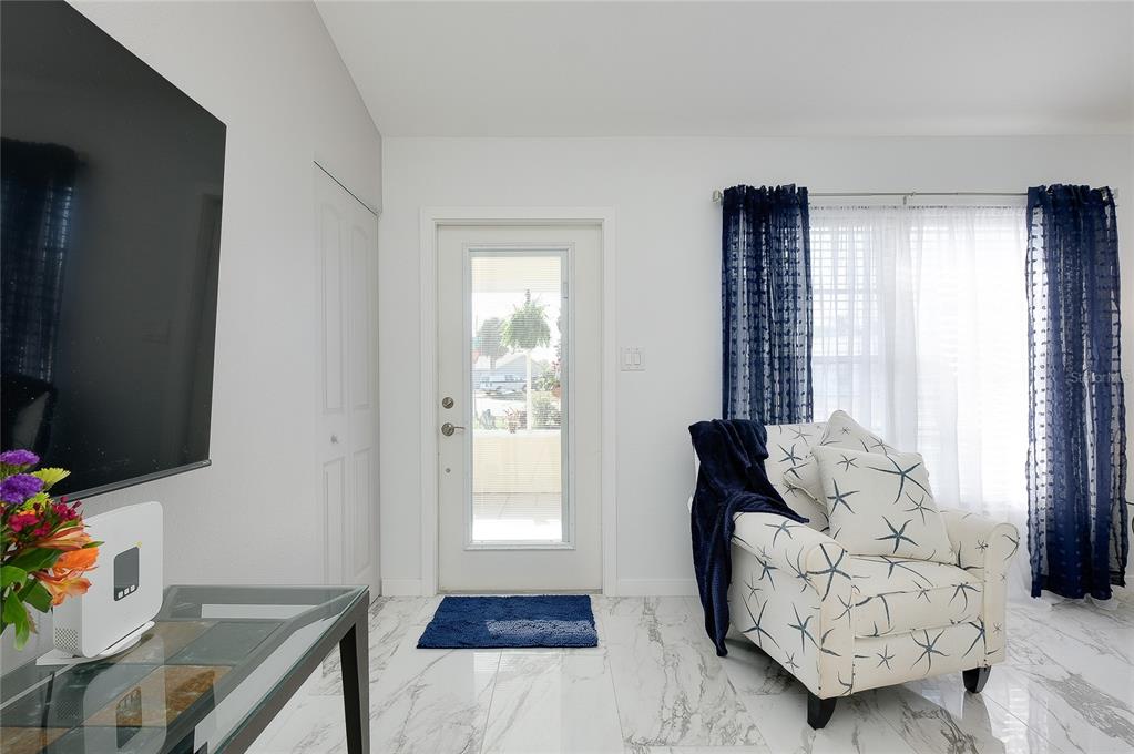 A living room features a white front door, marble-look flooring, and a patterned armchair — 6433 GRANGER ROAD, PORT CHARLOTTE, FL